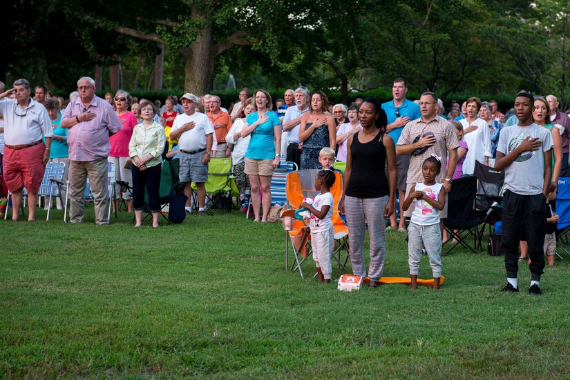 A group of attendees sing the national anthem during the final “Music Under the Stars” concert at Fort Eustis, Va., Aug. 25, 2016. The band provides music for headquarters and Training and Doctrine Command areas of interest by developing Soldier and family morale. (U.S. Air Force photo by Airman 1st Class Derek Seifert)