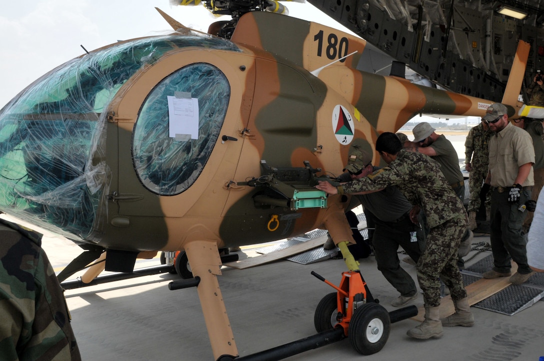 The first of four MD-530F Cayuse attack helicopters is unloaded from a C-17 Globemaster aircraft at Hamid Karzai International Airport in Kabul, Afghanistan, Aug. 25, 2016. Combined Security Transition Command - Afghanistan oversaw the transfer of four MD-530F Cayuse attack helicopters and a C-130H Hercules transport aircraft to the Afghan air force. Navy photo by Lt. Christopher Hanson