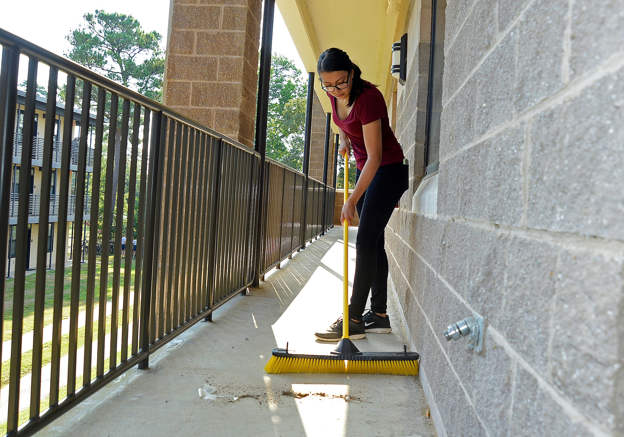 U.S. Air Force Airman 1st Class Ariel Vargas, 20th Logistics Readiness Squadron logistics planner, sweeps dirt off a dormitory walkway at Shaw Air Force Base, S.C., Aug. 27, 2016. The dorm cleanup focused on tidying up the exterior with power-washing the building and landscaping around the dorms. (U.S. Air Force photo by Airman BrieAnna Stillman)