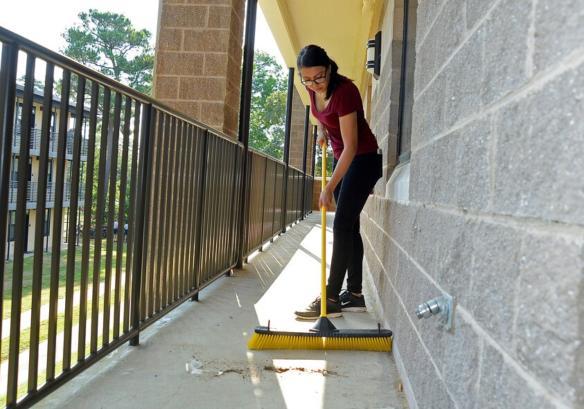 U.S. Air Force Airman 1st Class Ariel Vargas, 20th Logistics Readiness Squadron logistics planner, sweeps dirt off a dormitory walkway at Shaw Air Force Base, S.C., Aug. 27, 2016. The dorm cleanup focused on tidying up the exterior with power-washing the building and landscaping around the dorms. (U.S. Air Force photo by Airman BrieAnna Stillman)