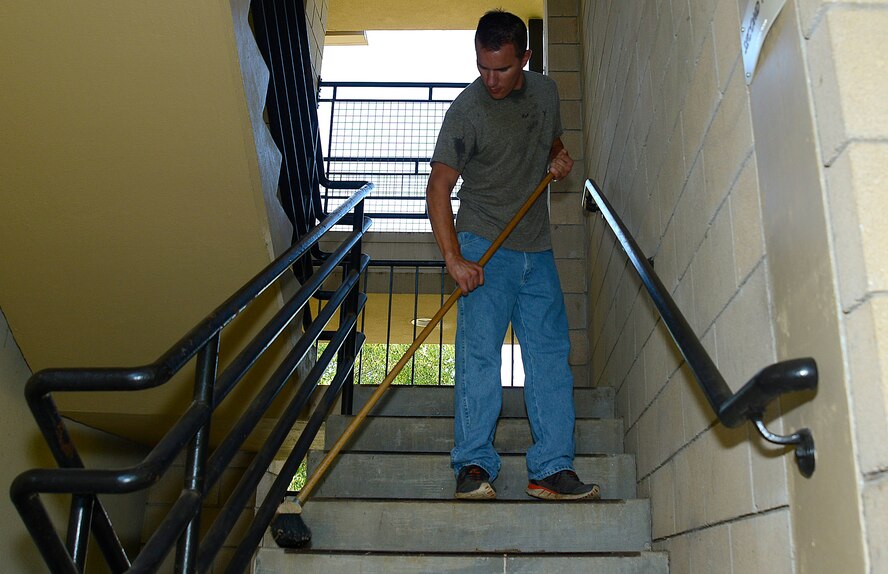 U.S. Air Force Senior Airman Jordan Sigmon, 20th Force Support Squadron personnel apprentice, sweeps dirt off the stairs of a dormitory at Shaw Air Force Base, S.C., Aug. 27, 2016. The dorm cleanup was an opportunity for Airmen to work side-by-side with their supervisors. (U.S. Air Force photo by Airman BrieAnna Stillman)