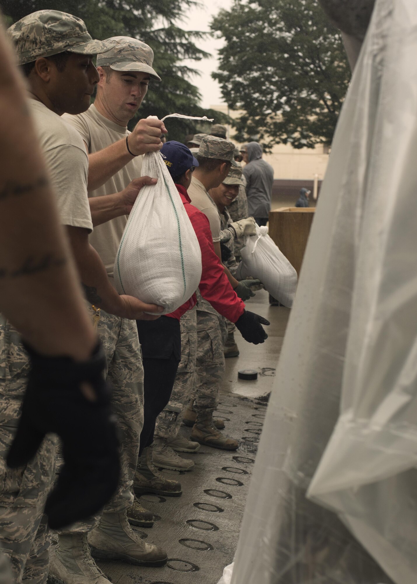 Airmen pass sand bags down a body line to be placed near potential flood areas in preparation for Typhoon Lionrock at Yokota Air Base, Japan, Aug. 29, 2016. Approximately 5,000 sand bags were filled and strategically placed around Yokota in preparation for Typhoon Lionrock. One week earlier, Typhoon Mindulle dropped nearly 10 inches of rain and heavy winds on Yokota, flooding many buildings and causing power outages for nearly 1,000 base residents. (U.S. Air Force photo by Airman 1st Class Donald Hudson/Released)