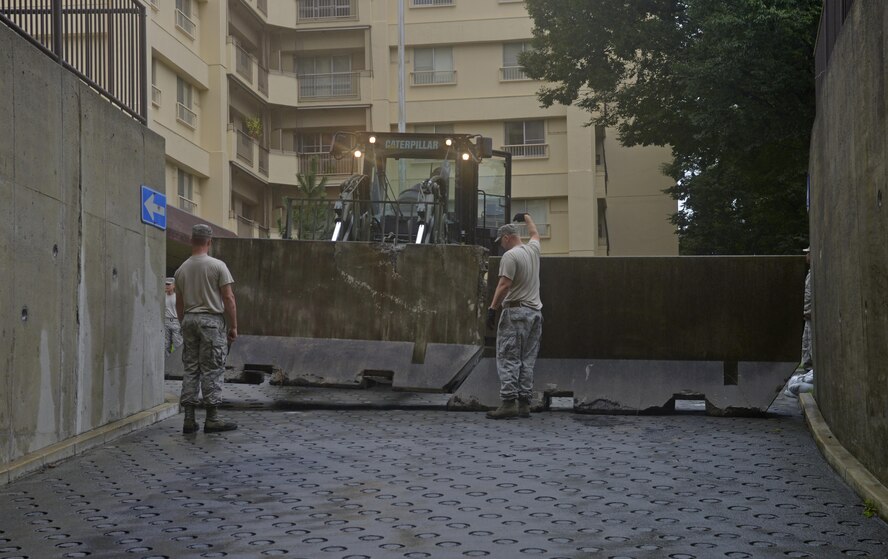 Members of the 374th Civil Engineer Squadron place cement barriers at the entrance of a tower’s basement pathway in preparation of Typhoon Lionrock at Yokota Air Base, Japan, Aug. 29, 2016. In the aftermath of the Typhoon Mindulle, more than 300 families were relocated in the wake of the storm due to flooding causing power outages in multiple towers. (U.S. Air Force photo by Senior Airman David Owsianka/Released)