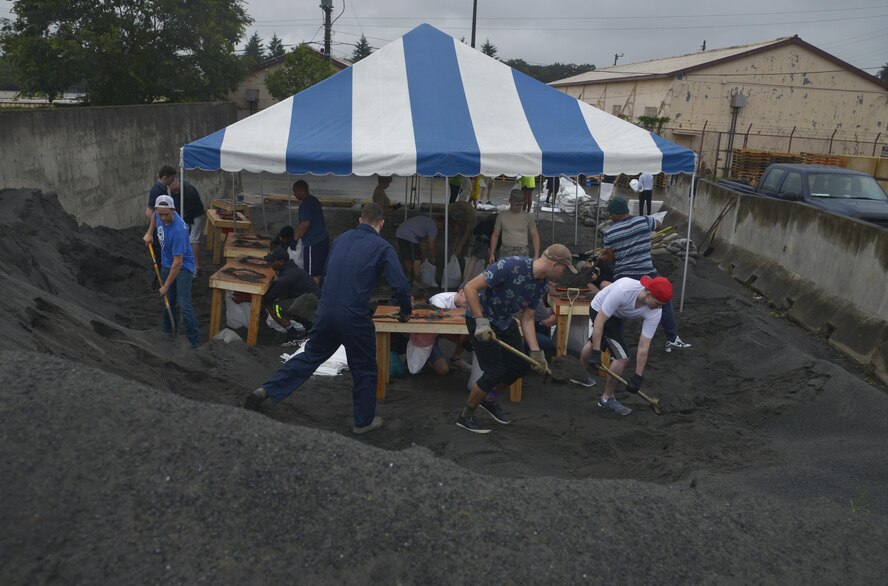 Airmen shovel dirt for sand bags at Yokota Air Base, Japan, Aug. 27, 2016. The Airmen were split into different groups to expedite the process; some personnel placed dirt in sand bags, some tied knots on the bags, and others placed the sand bags onto crates. (U.S. Air Force photo by Senior Airman David Owsianka/Released)