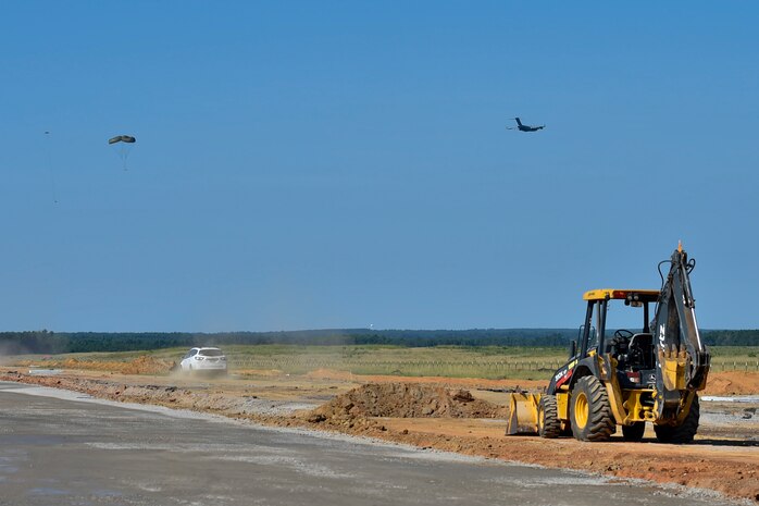 A C-17 Globemaster II aircraft drops cargo at the North Auxiliary Airfield in North, South Carolina, while a stone base is laid down for a new landing zone, Aug. 25, 2016. The airfield directly supports the 437th and 315th Airlift Wing's C-17 aircrew and proficiency training. (U.S. Air Force Photo/Airman Megan Munoz)