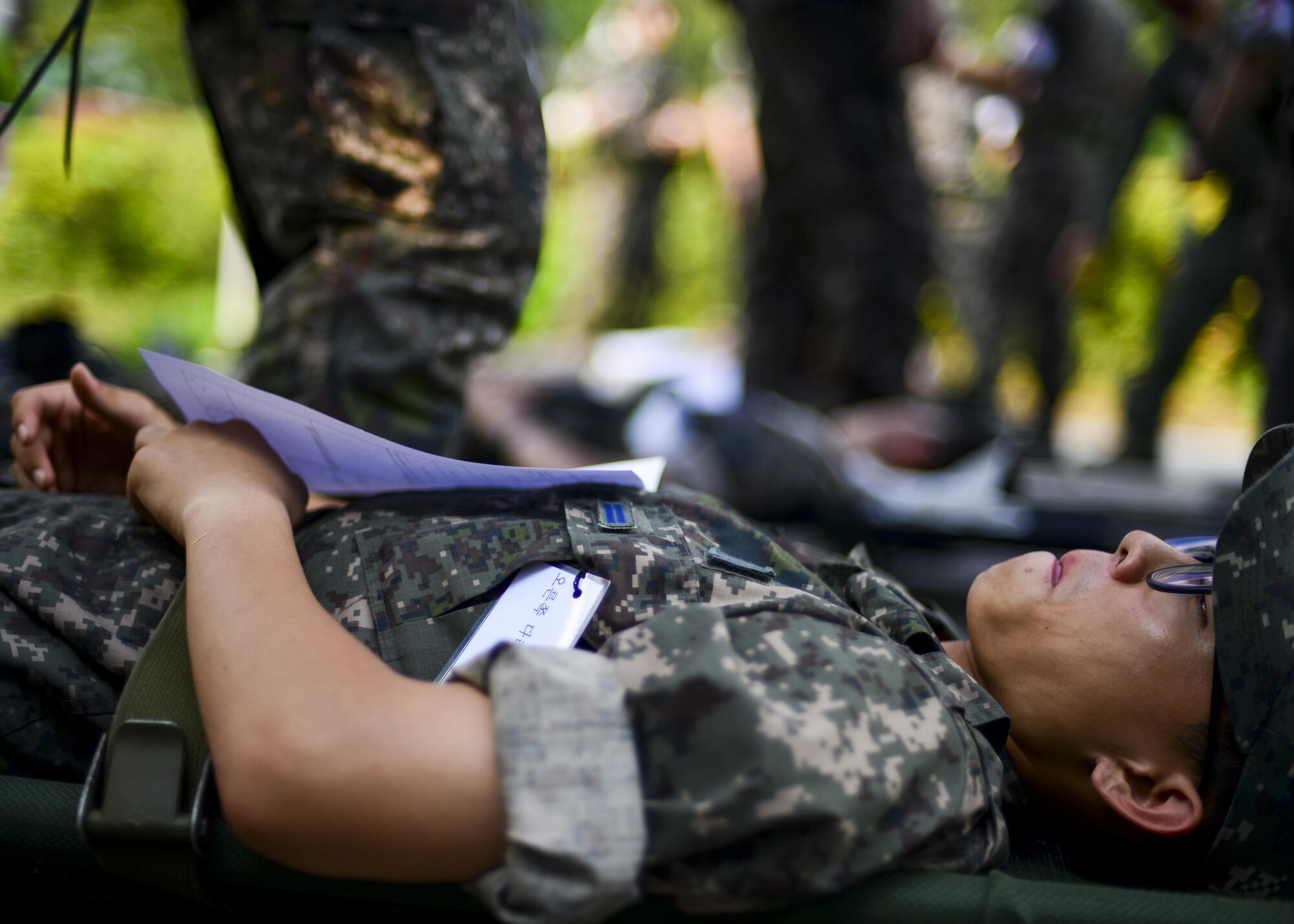 A Republic of Korea air force airman simulates waiting for treatment during a joint mass-casualty medical exercise at Osan Air Base, Republic of Korea, Aug. 22, 2016. ROKAF medical personnel worked with 51st Medical Group medics on triaging and transporting victims of a simulated bombing to proper medical facilities. (U.S. Air Force photo by Senior Airman Victor J. Caputo)