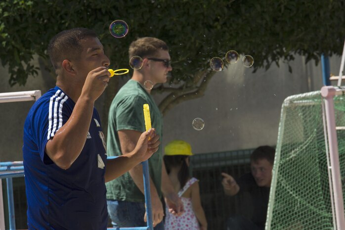 A volunteer with the Marine Memorial Chapel blows bubbles at Midoro Hoikuen in Iwakuni, Japan, Aug. 23, 2016. Marine Corps Air Station Iwakuni volunteers participated in singing, blowing bubbles and a water fight with local Japanese children during a community relations preschool visit. (U.S. Marine Corps photo by Lance Cpl. Joseph Abrego)