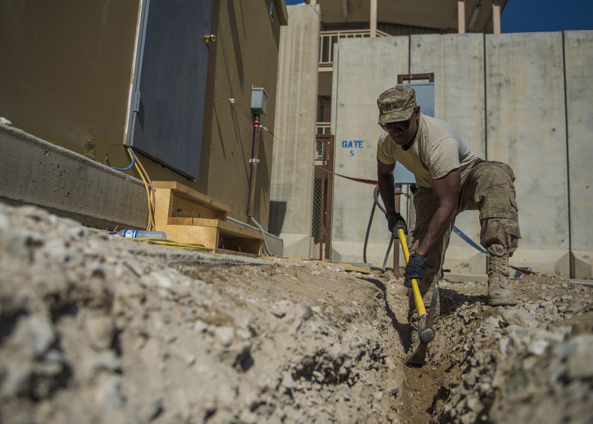 Senior Airman Leon Michael, 455th Expeditionary Civil Engineer Squadron electrical journeyman, uses a pick ax to dig up dirt, Bagram Airfield, Afghanistan, Aug. 31, 2016. The ECES electricians laid service wire to provide electricity for a new Airman’s Attic and ministry center. (U.S. Air Force photo by Senior Airman Justyn M. Freeman)