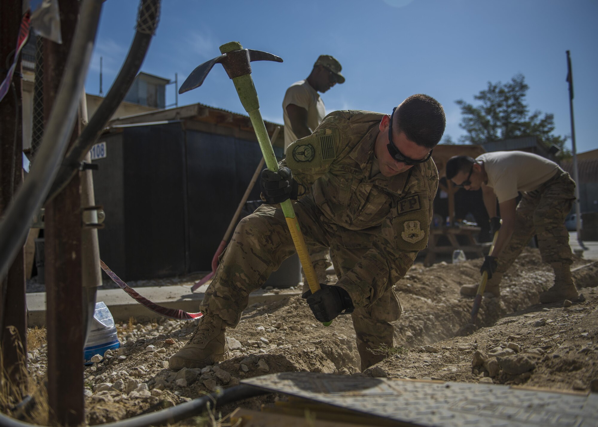 Airmen from the 455th Expeditionary Civil Engineer Squadron run service wire through the ground, Bagram Airfield, Afghanistan, Aug. 31, 2016. Electricians paired with the ECES structures team to renovate and provide electricity to a new Airman’s Ministry Center and Airman’s Attic. (U.S. Air Force photo by Senior Airman Justyn M. Freeman)