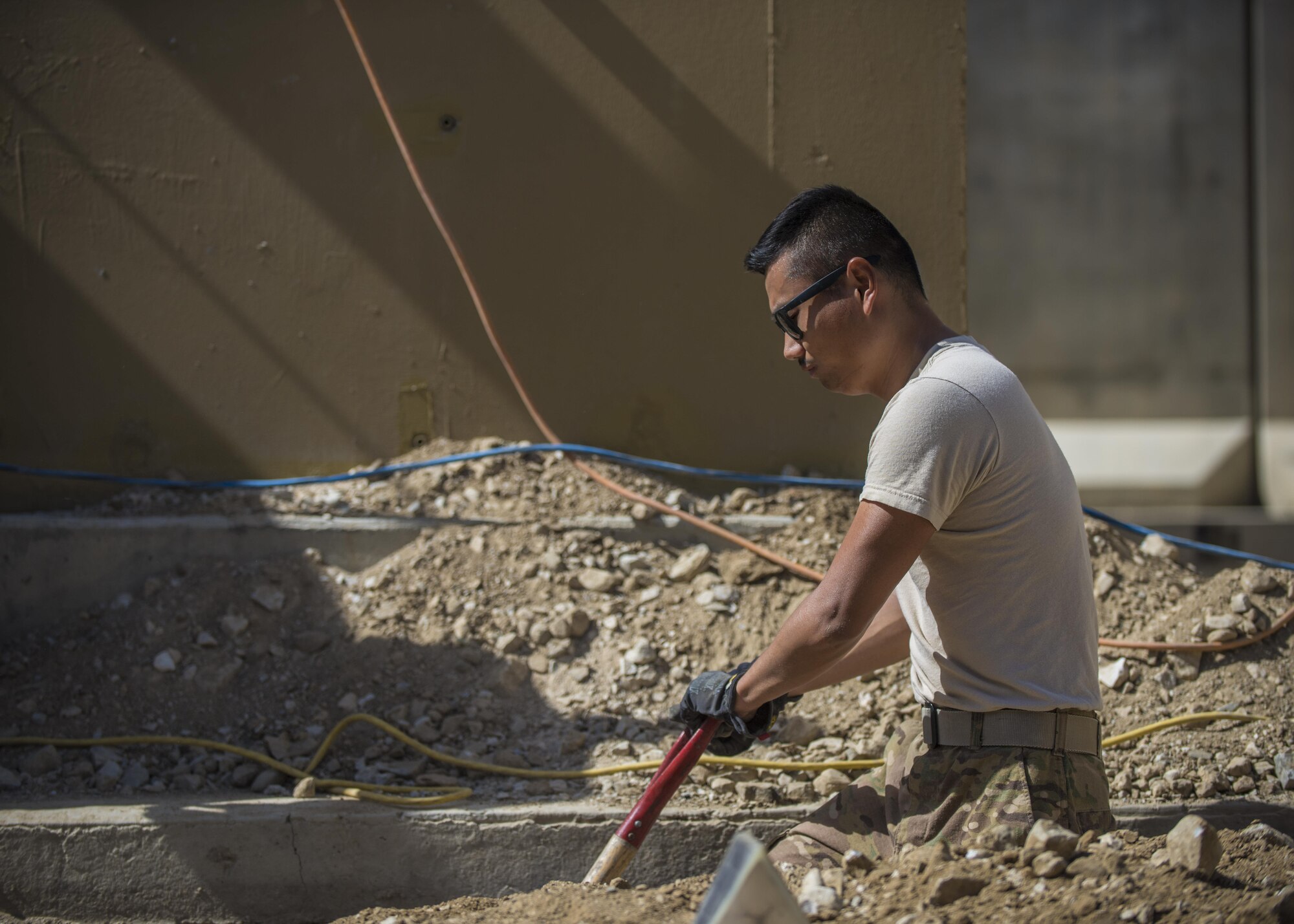 Senior Airman Tony Tang, 455th Expeditionary Civil Engineer Squadron electrical journeyman, shovels dirt out of a trench, Bagram Airfield, Afghanistan, Aug. 31, 2016. Electricians paired with the ECES structures team to renovate and provide electricity to a new Airman’s Ministry Center and Airman’s Attic. (U.S. Air Force photo by Senior Airman Justyn M. Freeman)