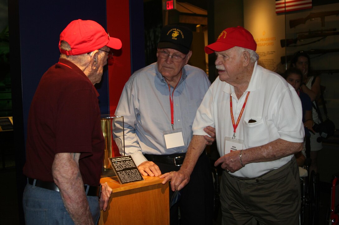 World War II veterans Ear Lance, Pat Patrick, and Mike Arrand examine an artillery round fired by their battalion, the 2nd 155 Howtizer Battalion, during the Guadalcanal campaign in 1942.