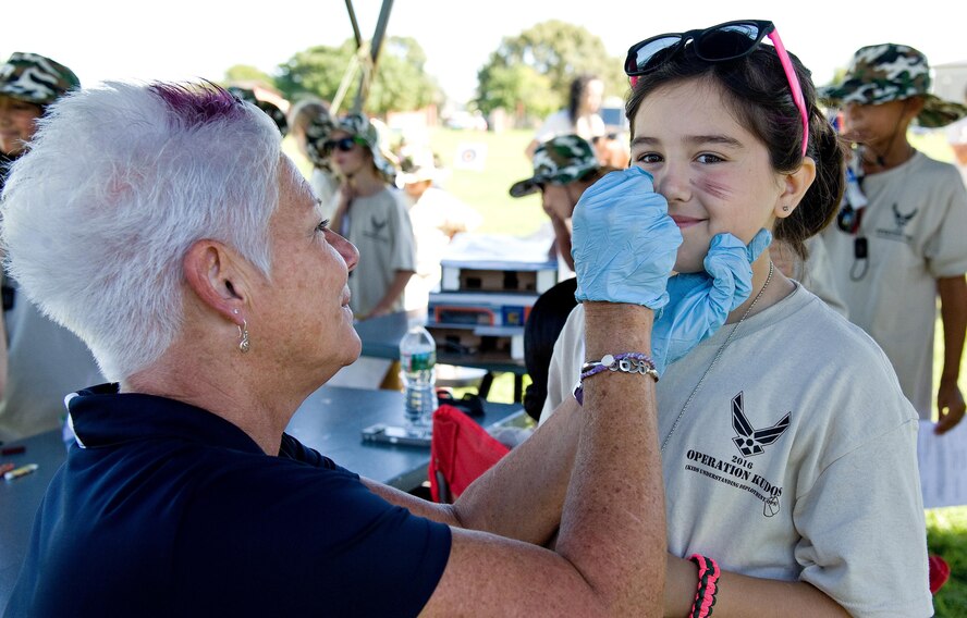Dawne Nickerson-Banez, 436th Airlift Wing community relations chief, paints the face of Joey Fleegal, in the deployment processing line during the Kids Understanding Deployment Operations/Teachers Understanding Deployment Operations event Aug. 23, 2016, on Dover Air Force Base, Del. Nickerson-Banez and other volunteers helped paint the faces of children on each of the six chalks that simulated the deployment process. (U.S. Air Force photo by Roland Balik)