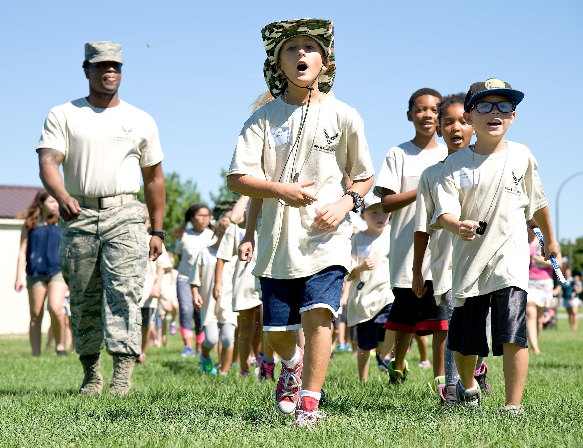 Tech. Sgt. Julio Fareaux, 436th Logistics Readiness Squadron NCO in charge of flight service center, left, marches children in Chalk 5 to their next station in the deployment processing line during the Kids Understanding Deployment Operations/Teachers Understanding Deployment Operations event Aug. 23, 2016, on Dover Air Force Base, Del. More than 240 children were registered for the 11th annual event sponsored by the Airman & Family Readiness Center. (U.S. Air Force photo by Roland Balik)