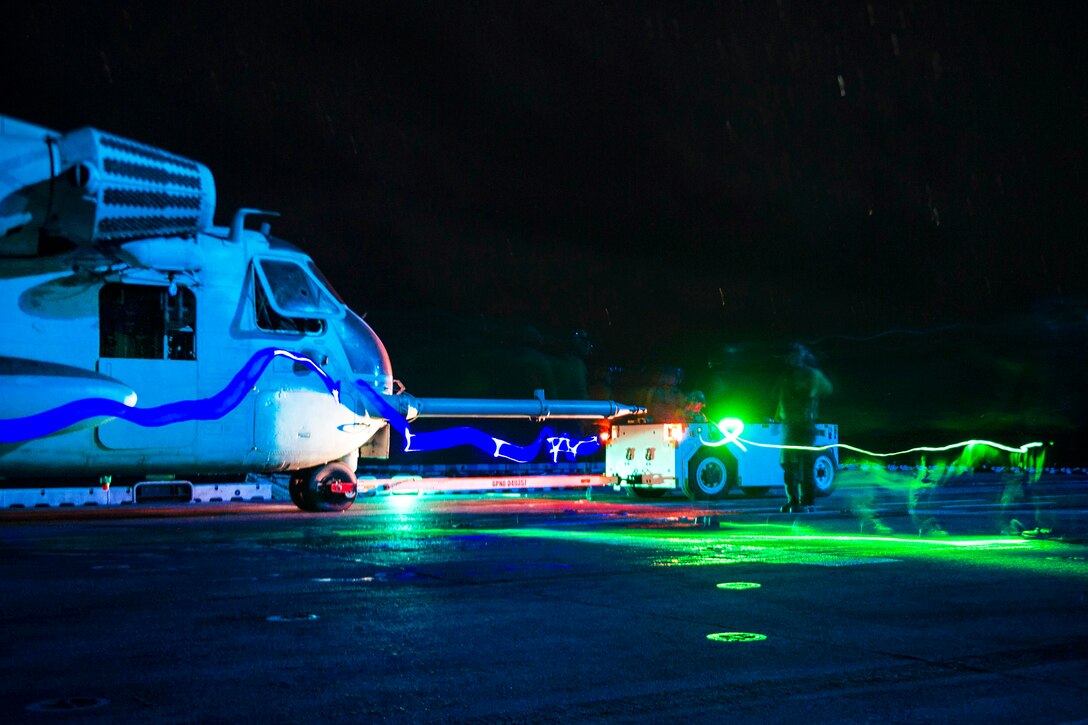 Sailors and Marines tow a CH-53E Super Stallion helicopter during night operations on the flight deck of amphibious assault ship USS Boxer in the Pacific Ocean, Aug. 26, 2016. Navy photo by Petty Officer 3rd Class Michael T. Eckelbecker