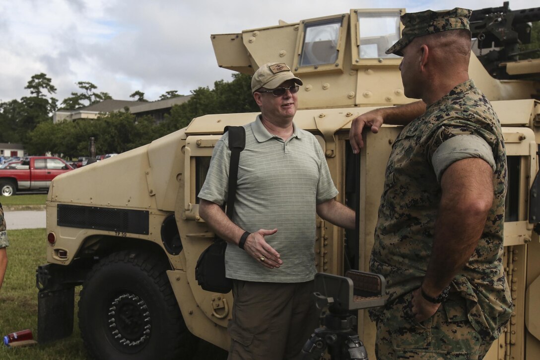 Marine veteran Sgt. Patrick Melton, formerly with 1st Battalion, 6th Marine Regiment, 2nd Marine Division trade stories about his enlistment with MGySgt. David Ruble, the operations chief with 1/6 at Camp Lejeune, N.C., Aug. 29, 2016. 1/6 had static displays, gave a tour around 6th Marine Regiment and organized a reunion for veterans who survived a helicopter crash while attached the 22nd Marine Expeditionary Unit and 1/6 in 1986 . (U.S. Marine Corps photo by Lance Cpl. Miranda Faughn)