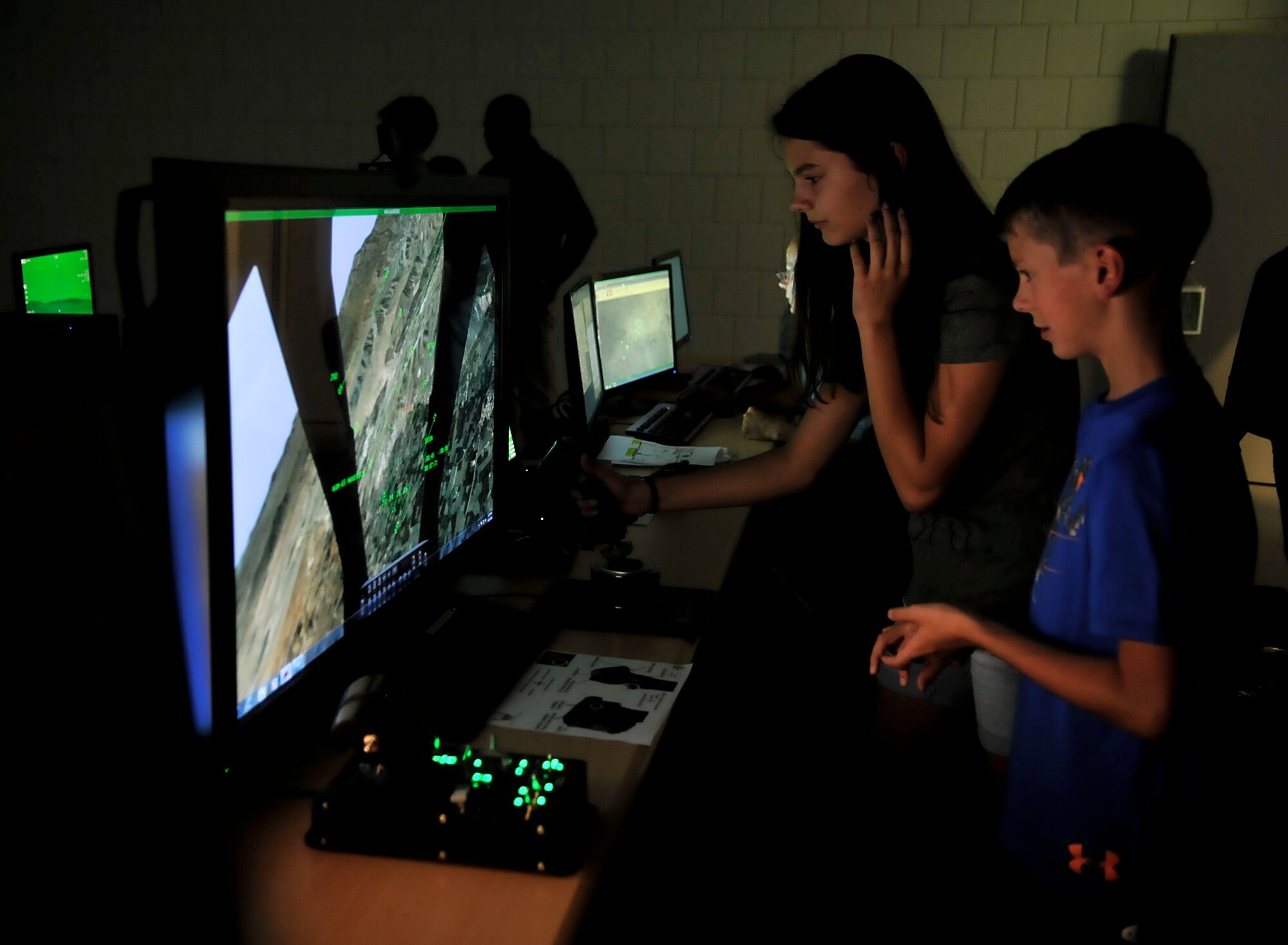 Family members test out a flying simulation during an open house Aug. 25, 2016, at Einsiedlerhof Air Station, Germany. The simulators are modeled after different areas of deployed locations and allow Airmen to train and hone their skills for real-world situations. (U.S. Air Force photo/Senior Airman Larissa Greatwood) 
