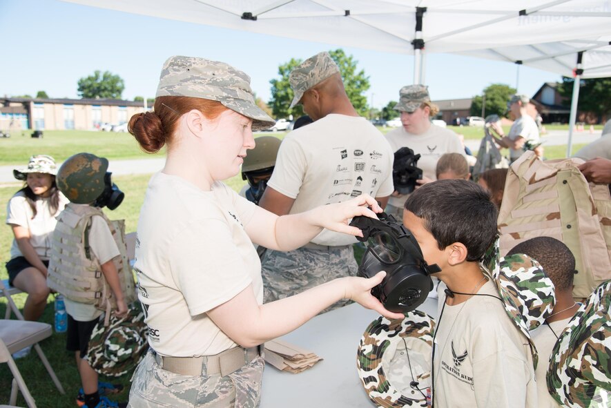 Senior Airman Lydia Brower, 436th Logistics Readiness Squadron, helps a young child don a gas mask during the Kids/Teachers Understanding Deployment Operations event  Aug. 23, 2016, at Dover Air Force Base, Del. The annual event helps school age children of active duty service members and their teachers understand what it's like to deploy overseas. (U.S. Air Force photo by Mauricio Campino)