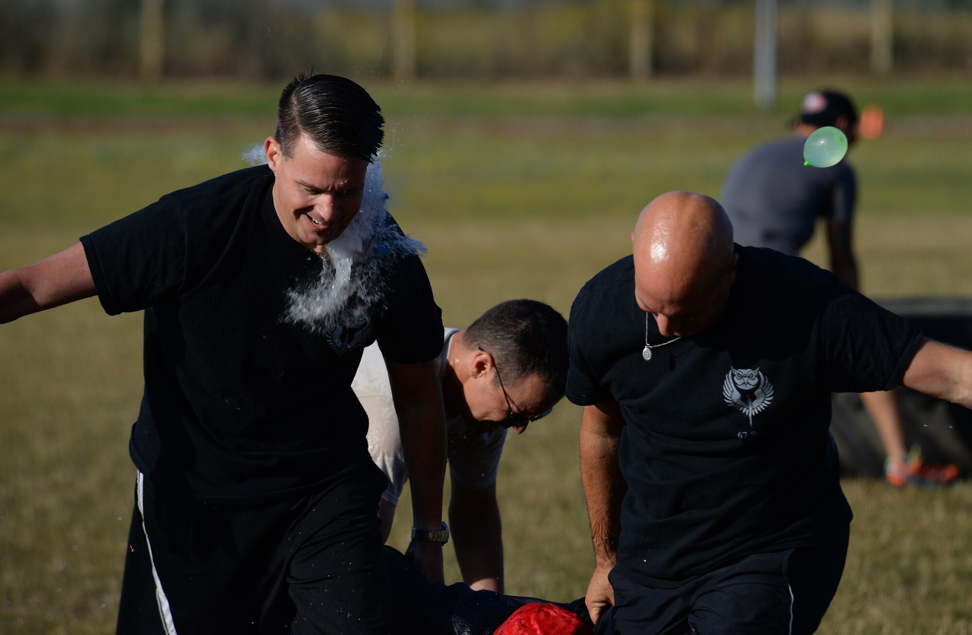 Air commandos from the 352d Special Operations Wing drag a dummy during the Highland Games Sports and Family Day Aug. 26, 2016, on RAF Mildenhall, England. The event opened with a leadership relay race where participants had to sprint, flip a tire and carry a dummy across the finish line while competitors threw water balloons at them. (U.S. Air Force photo by Staff Sgt. Micaiah Anthony)