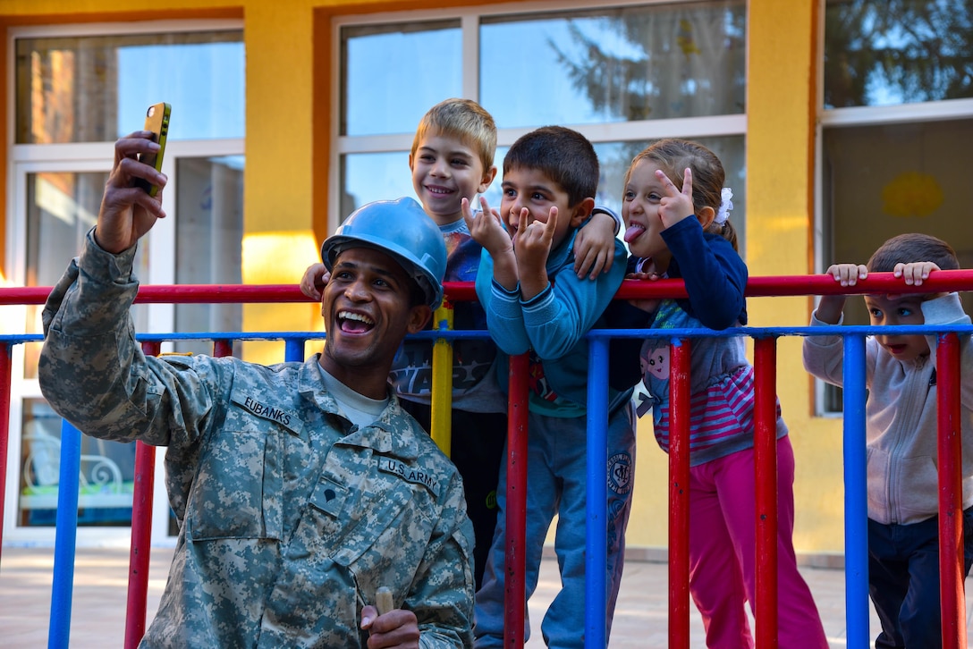 U.S. Soldier with the 375th Engineer Company, Huntsville, Alabama, takes a selfie with kindergarten children during a Humanitarian Civil Assistance project, Kalifarevo, Bulgaria, Aug. 26, 2016. As a part of the European Command’s (EUCOM) Humanitarian a Civic Assistance Program, the U.S. Army reserve 457th Civil Affairs Battalion, the 375th Engineer Company, U.S. Air Force National Guard 164th Civil Engineer Squadron and the Bulgarian Army collaborate to renovate a kindergarten. (U.S. Army photo by Spc. Nathanael Mercado)