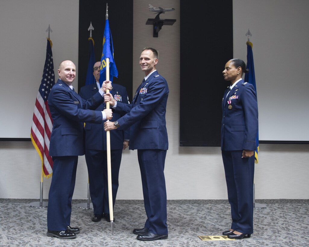 Col. Norman West (center) accepts the 412th Medical Group guidon from Brig. Gen. Carl Schaefer, 412th Test Wing commander, during a change of command ceremony held at the Airman and Family Readiness Center Aug. 26. West takes over from Col. Karen Cox-Dean (far right) who had been in command of the Desert Medics for more than two years. (U.S. Air Force photo by Joseph Gocong)