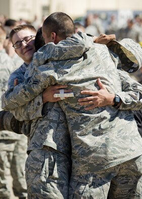 Airmen embrace after returning home from a deployment at Dock 9 at Minot Air Force Base, N.D., Aug. 29, 2016. Airmen from the 5th Bomb Wing were deployed to Andersen Air Force Base, Guam, in support of the continuous bomber presence. (U.S. Air Force photo/Airman 1st Class J.T. Armstrong)