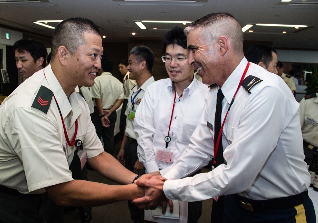 Col. Luis Pomales (right), director, Army Reserve Engagement Team-Japan, presents an ARET-J coin to a Japan Ground Self-Defense Force Reserve Component service member during a formal dinner hosted at the Sky View Restaurant in Camp Ichigaya, Japan, Aug. 29, 2016. The JGSDF senior leadership selected approximately 60 Reserve Component service members to Camp Ichigaya to participate in a week-long symposium that promoted esprit de corps between the reserve and its active duty component through classroom assignments, field exercises and social events. The JGSDF invited Pomales to speak about the mission and capabilities of the U.S. Army Reserve and how they enhance the bilateral partnership between Japan and the United States. (U.S. Army photo by Sgt. John Carkeet, U.S. Army Japan)