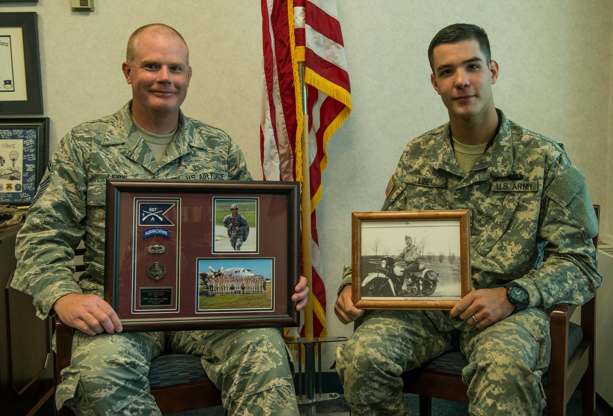 Senior Master Sgt. Daniel Libby, 618th Air Operations Center first sergeant, holds a picture frame containing the accomplishments and a picture of his son Pvt. Michael Libby, an armorer in the Army, while Michael holds a picture of his great grandfather, Scott Air Force Base, Ill., Aug. 8, 2016.