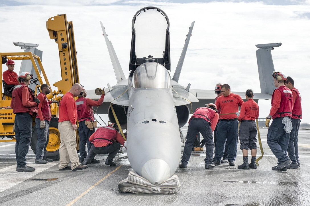 Sailors tighten straps on a jet during training to simulate the failing of an aircraft's landing gear while on the USS Ronald Reagan in the Pacific Ocean, Aug. 29, 2016. The Reagan is defending collective maritime interests of the United States and its allies and partners in the Indo-Asia-Pacific region. Navy photo by Seaman Jamaal Liddell