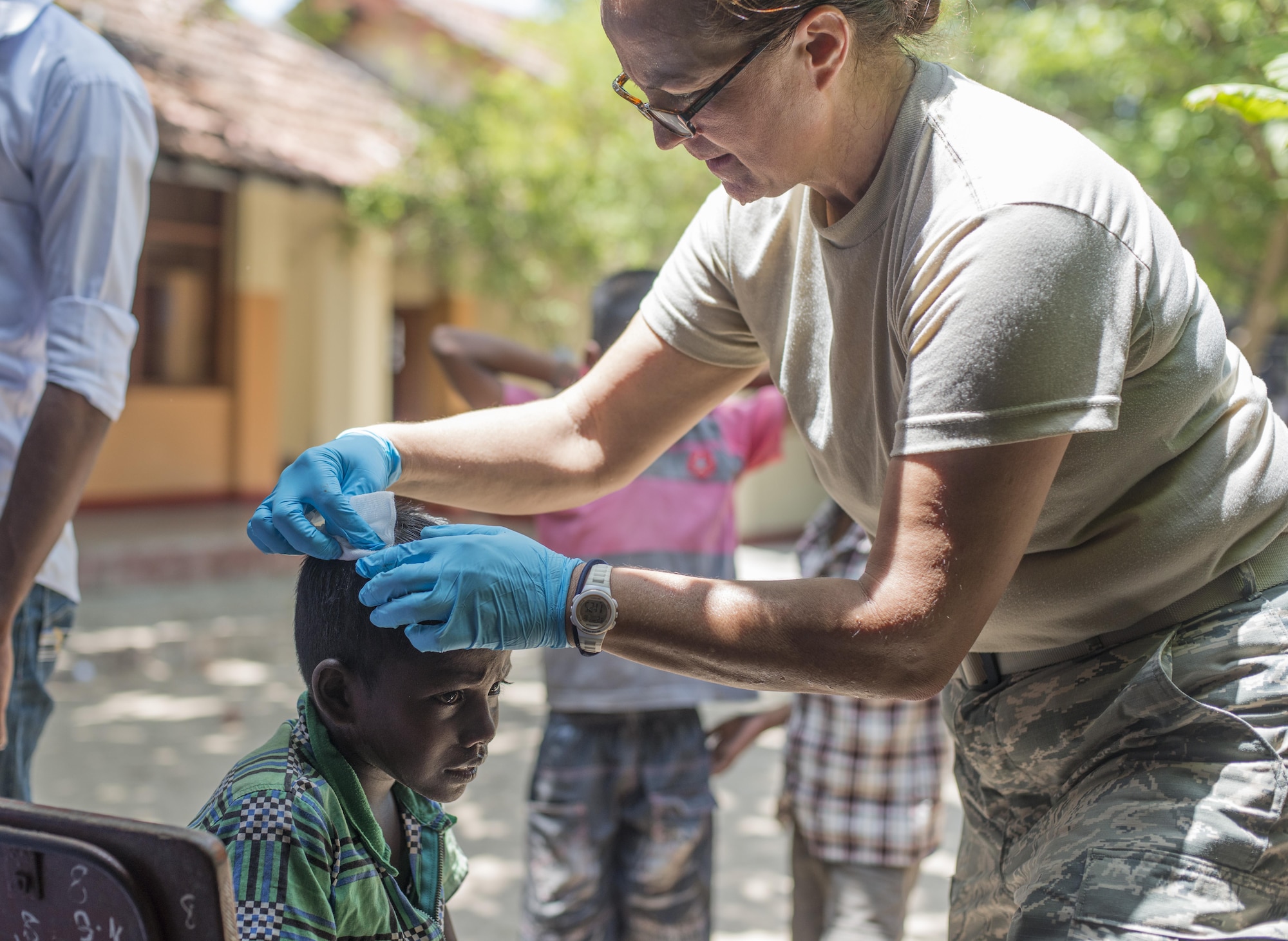 U.S. Air Force Staff Sgt. Victoria Campbell, 154th Medical Group medic, treats a childs head wound during Pacific Angel (PACANGEL) 16-3 in Jaffna, Sri Lanka, Aug. 20, 2016. PACANGEL is a total force, joint and combined humanitarian assistance/civil military operation led by U.S. Pacific Air Forces. Assistance during PACANGEL includes general health, dental, optometry and physical therapy. (U.S. Air Force photo by Senior Airman Brittany A. Chase)