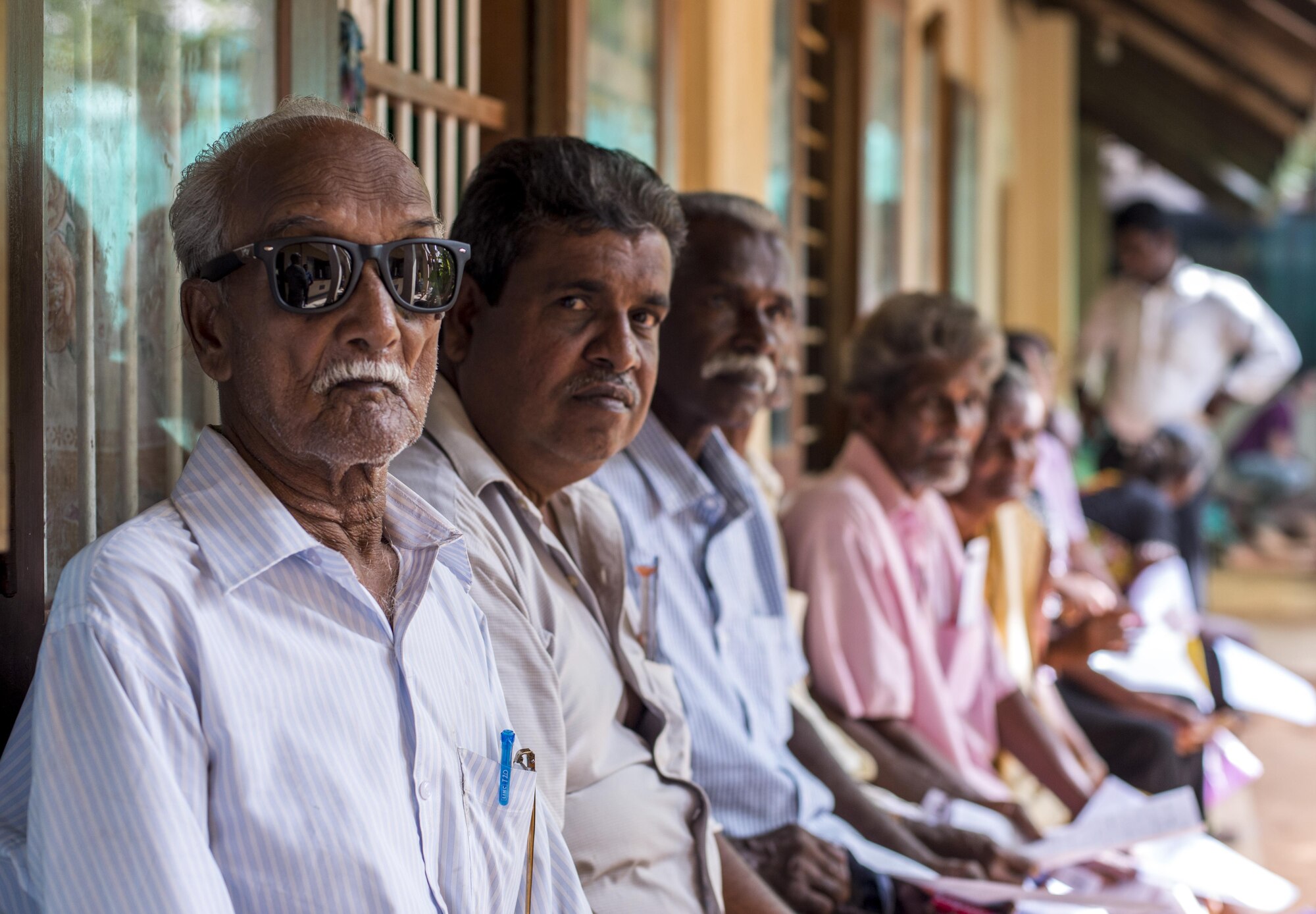 A Sri Lanka native await medical care while wearing a new pair of sunglasses provided by optometry during Pacific Angel (PACANGEL) 16-3 in Jaffna, Sri Lanka, Aug. 17, 2016. PACANGEL is a total force, joint and combined humanitarian assistance/civil military operation led by U.S. Pacific Air Forces. Assistance during PACANGEL included general health, dental, optometry and physical therapy. (U.S. Air Force photo by Senior Airman Brittany A. Chase)