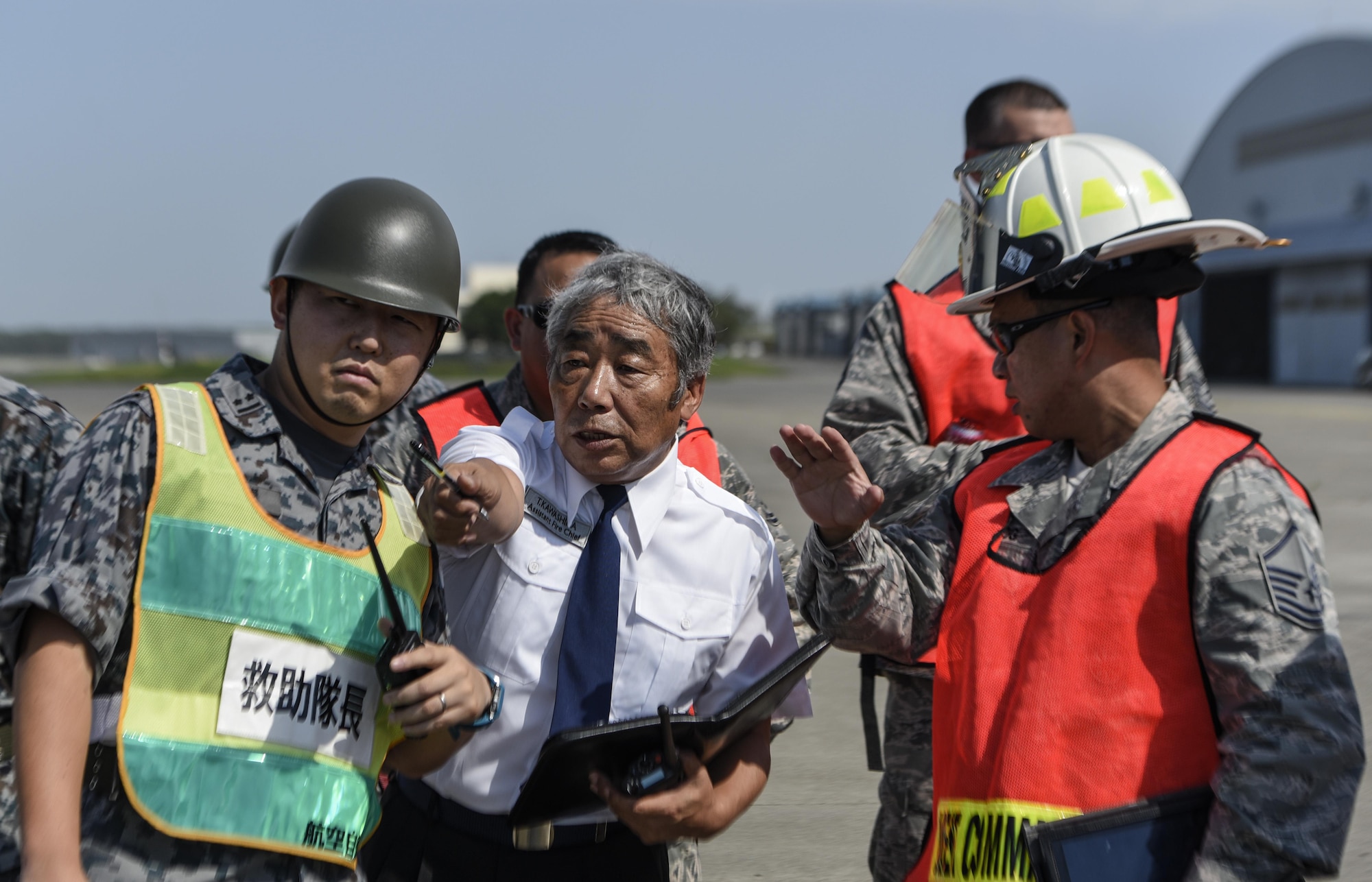 Japan Air Self Defense Force member 1st Lt. Murase Toshia, left, and Kawashima Toshinobu, an assistant fire chief, center, discuss with U.S. Air Force Master Sgt. Francis Tagalog, a deputy fire chief and incident commander assigned to 35th Civil Engineer Squadron, the situation and roles of the firemen from both the JASDF and USAF during a bilateral emergency management exercise at Misawa Air Base, Japan, Aug. 31, 2016. During the planning stages both sides established the counterparts, chain of command and how all agencies are going to respond. (U.S. Air Force photo by Airman 1st Class Sadie Colbert)
