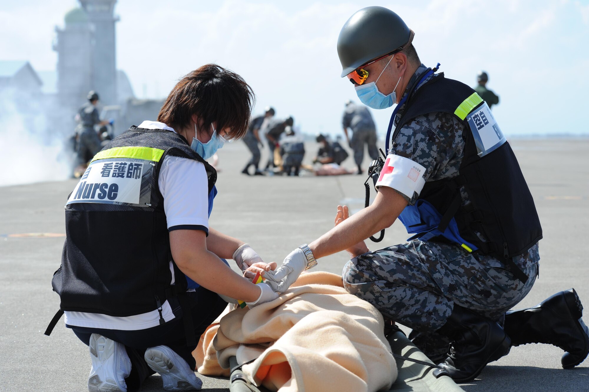 Misawa Hospital nurse, left, and Japan Air Self Defense Force service member check the vitals of a patient during a bilateral emergency management exercise at Misawa Air Base, Japan, Aug. 31, 2016. The exercise prepared USAF and JASDF members to appropriately respond to an improvised explosive device detonation during an air show. (U.S. Air Force photo by Tech. Sgt. April Quintanilla)