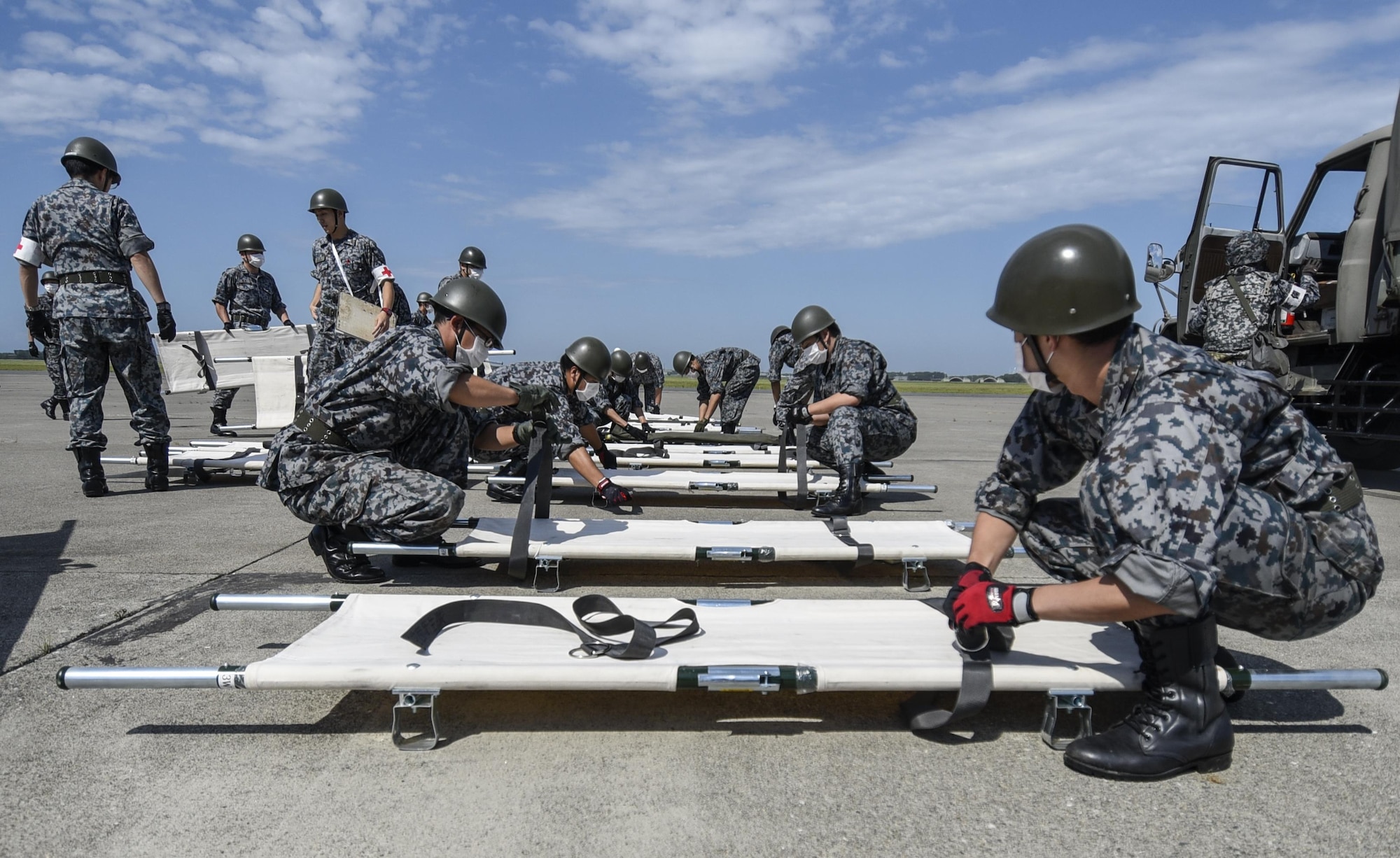 Japan Air Self Defense Force personnel prepare litters during a bilateral emergency management exercise at Aug. 31, 2016. USAF and JASDF agencies including security forces squadrons, medical and fire departments responded to approximately 60 USAF and Japanese personnel who simulated various injuries that could occur after an explosion. (U.S. Air Force photo by Airman 1st Class Sadie Colbert)