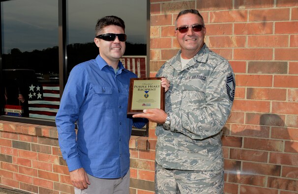 Purple Heart recipient, Josiah Swanson of Sioux City, Iowa is presented with a Purple Heart plaque by Iowa Air National Guard Chief Master Sgt. Barry Bower in Sioux City, Iowa on Augusts 31, 2016. The plaque was presented on behalf of Support Siouxland Soldiers in commemoration of Purple Heart day. Swanson was injured in Iraq while serving in the United States Marine Corps in 2006.