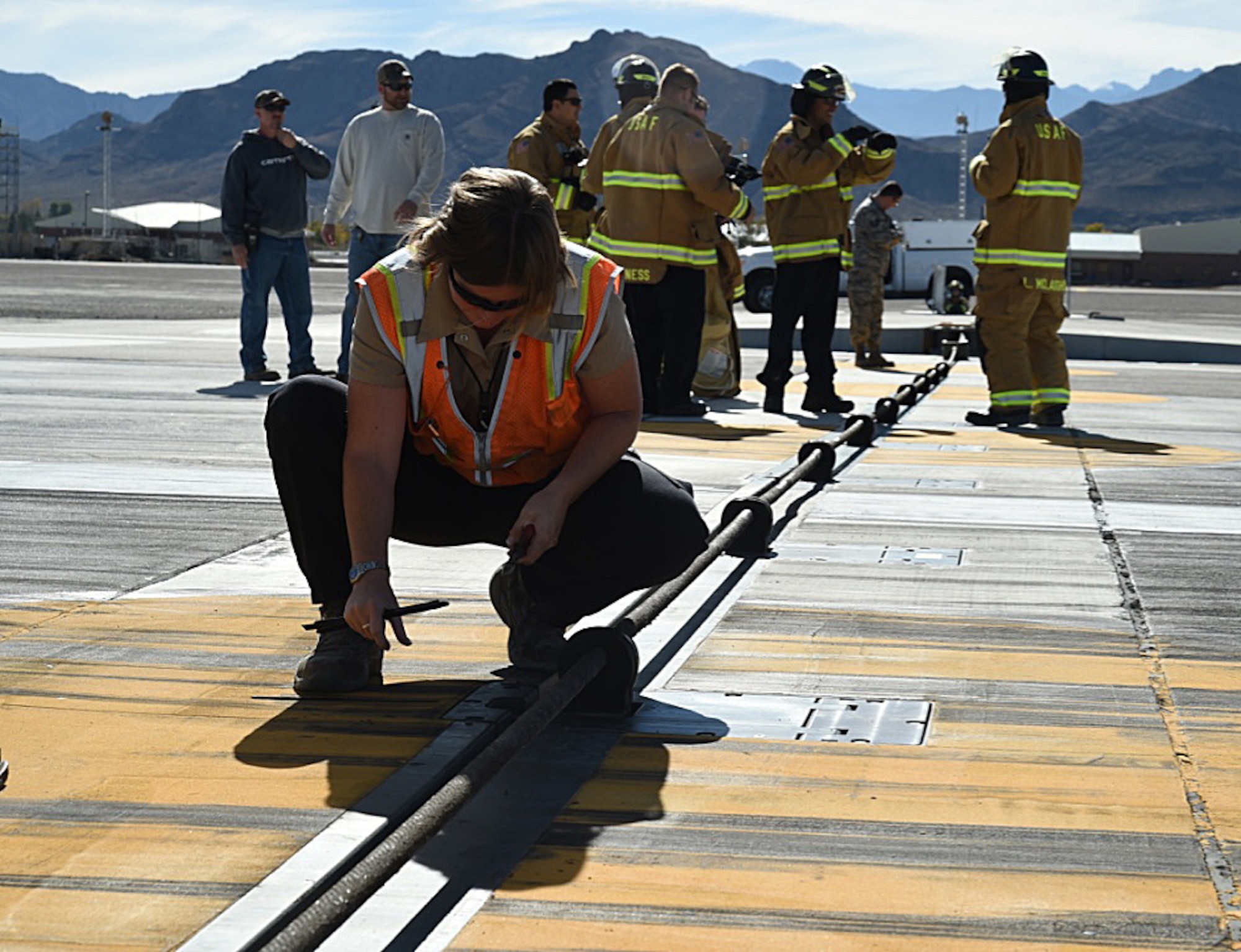 A powered support systems technician with the Nellis Testing and Training Range’s Support Squadron examines the arresting system Nov. 15, 2016, at Creech Air Force Base, Nev. The purpose of an active aircraft arresting system is to assist in decelerating aircraft during emergency situations.  (U.S. Air Force photo by Airman 1st Class James Thompson)