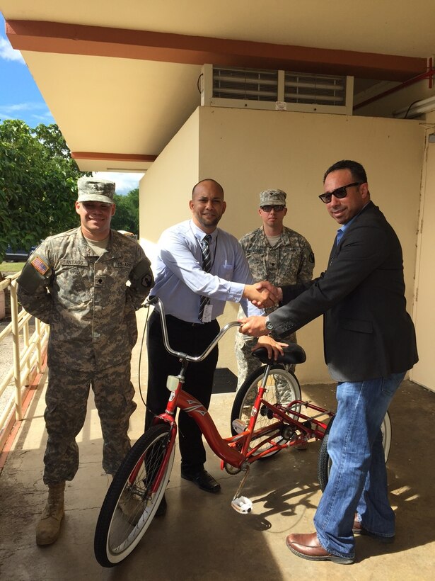 (Left to Right) Spec. Xavier Santiago, Mr. Hector Soto Rehabilitation Director for La Casa del Veterano, Spec. Calvin Velazquez, and Command Sgt. Maj. Rene Berlingeri, AVEN President, pose for a photo with one of the new bicycles donated to La Casa del Veterano, November 30th.