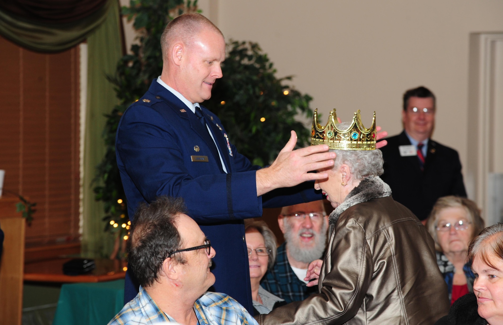 Lt. Col. Shane Lensgraf, 705th Munitions Squadron commander, crowns the Day of Love queen at Minot Air Force Base, N.D., Nov. 24, 2016. The Day of Love queen is presented to the oldest female in attendance at the event. (U.S. Air Force photo/Airman 1st Class Christian Sullivan)