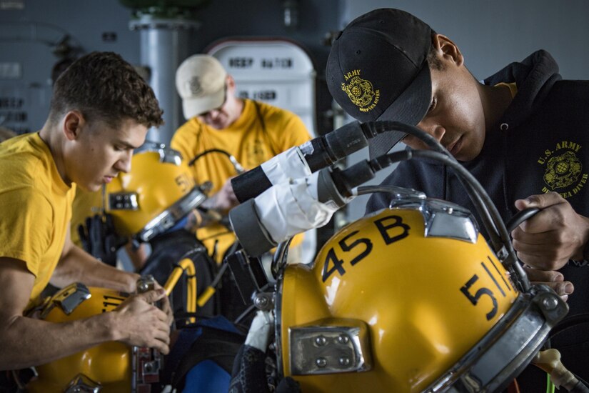 Soldiers with the 511th Engineer Dive Detachment from Fort Eustis, Va., help U.S. Army engineer divers don their helmets for diver training Nov. 18, 2016 while aboard the MG Charles P. Gross (Logistics Support Vessel-5) off the coast of Kuwait Naval Base. The unit executed various diving techniques and certified diving supervisors in emergency protocol throughout the exercise, Operation Deep Blue, enhancing the team’s overall readiness and ability to support U.S. Army Central missions. (U.S. Army photo by Sgt. Angela Lorden)