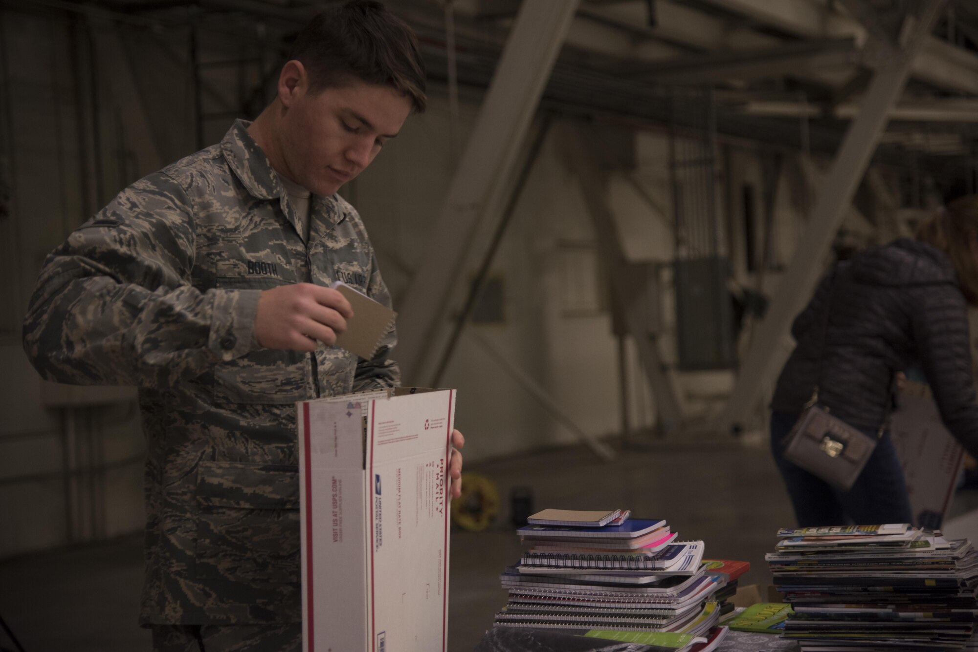 Airman Paul Booth, 92nd Aircraft Maintenance Squadron crew chief, places a notepad into a care package Dec. 1, 2016 at Fairchild Air Force Base. Booth volunteered to fill shipping boxes with various items such as soap, hot sauce, wet wipes and beef jerky. The boxes were packed as part of KREM 2 News Treats 2 Troops program that provides deployed military members with care packages. (U.S. Air Force photo/Senior Airman Nick J. Daniello)