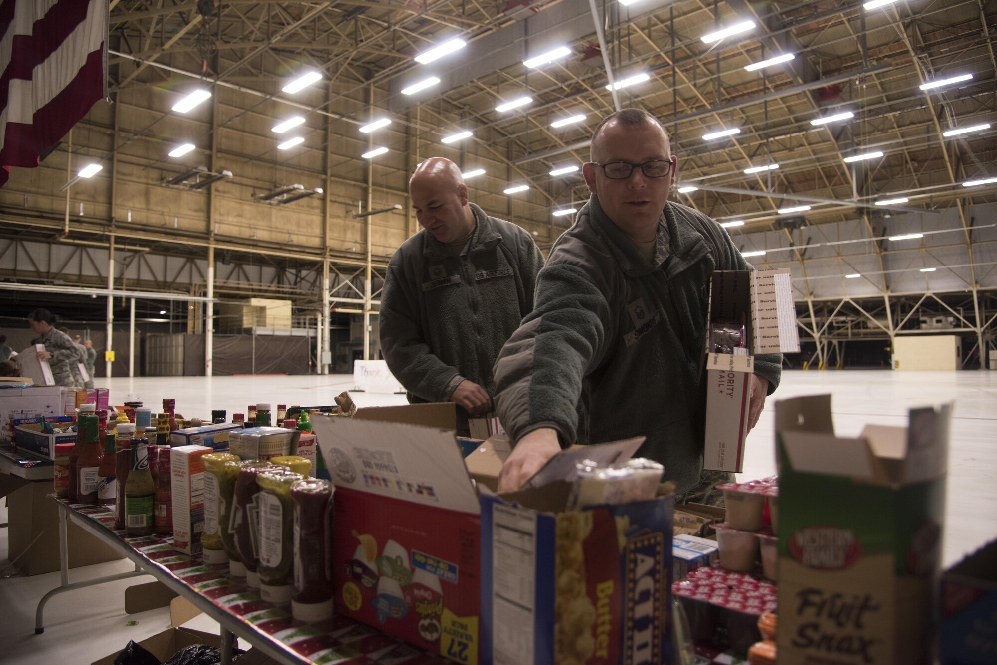 Master Sgt. Nicholas Ehman (left), 92nd Maintenance Squadron accessories flight assistant flight chief, and Master Sgt. Mark Simonds (right), Airman Family and Readiness Center superintendent, pack shipping boxes Dec. 1, 2016 at Fairchild Air Force Base. Ehman and Simonds were part of a team that consisted of more than 20 volunteers who packaged more than 400 shipping boxes. The care packages will be delivered to deployed military members as part of the KREM 2 News Treats 2 Troops program. (U.S. Air Force photo/Senior Airman Nick J. Daniello)