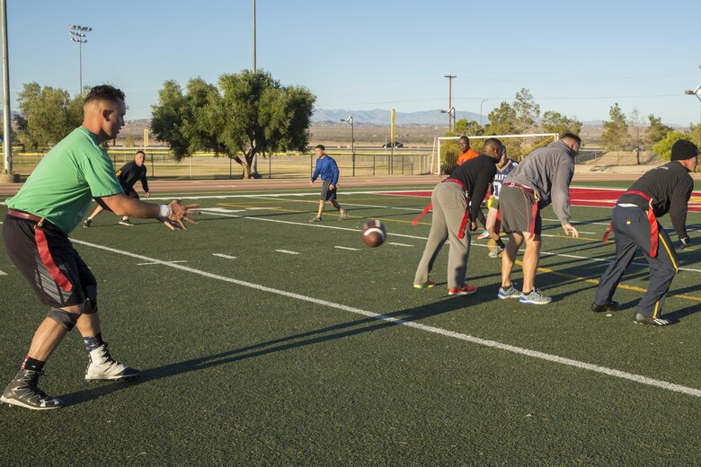 Staff Sgt. Richard Bousman, engineer equipment operator, Marine Wing Support Squadron 374, catches the ball off of the snap of the play during the MWSS-374 Turkey Bowl at Felix Field aboard the Marine Corps Air Ground Combat Center, Twentynine Palms, Calif., Nov. 22, 2016. MWSS-374 held the Turkey Bowl to build camaraderie within the senior leadership. (Official Marine Corps photo by Lance Cpl. Dave Flores/Released)