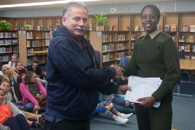 Cpl. Medina Ayala-Lo, combat correspondent, Headquarters Battalion, receives students’ letters from Don Henry, a teacher at La Contenta Middle School, during a visit to answer student’s questions in Yucca Valley, Calif., Nov. 30, 2016. Henry coordinates the event annually in an effort to teach his students about the military while giving them a chance to show their appreciation in the form of letters. (Official Marine Corps photo by Cpl. Julio McGraw/Released)