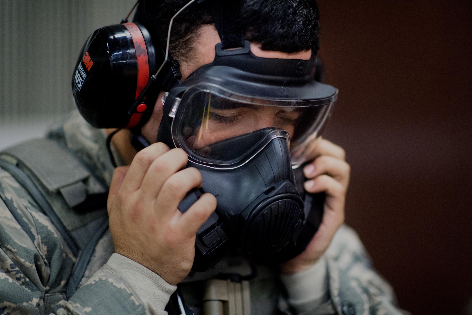 Airman 1st Class Sean Lebron, 374th Security Forces Squadron patrolman, dons a gas mask during a weapons qualification test at Yokota Air Base, Japan, Dec. 1. 2016. Airmen participate in the Combat Arms Training and Maintenance course to learn skills vital for defending themselves and their fellow Airmen downrange. (U.S. Air Force photo by Senior Airman Delano Scott/Released)