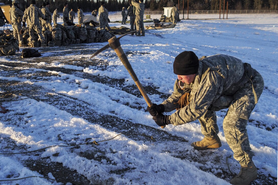 Army Spc. Joseph Feola uses an ax to enable soldiers to drive tent stakes into the frozen ground while conducting cold weather training in single-digit temperatures at Joint Base Elmendorf-Richardson, Alaska, Nov. 29, 2016. Feola is assigned to the 95th Chemical Company, 17th Combat Sustainment Support Battalion. Air Force photo by Justin Connaher