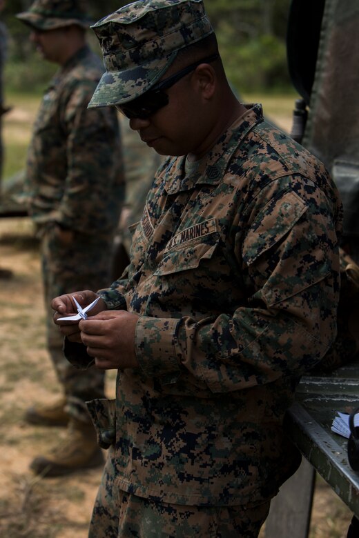 Staff Sgt. Ismael Esconde folds a paper crane during his free time in the field at Landing Zone Dodo, Okinawa on Nov. 2, 2016. Esconde wanted to make a difference during his six-month unit deployment program to Okinawa, Japan with Headquarters and Service Company, 3rd Battalion, 3rd Marine Regiment as the substance abuse control officer. He heard about the Legend of 1,000 Cranes and thought it would be a good way to show respect to the hospitals and nursing homes to which he gifted them. Esconde is from Los Angeles, California. (U.S. Marine Corps photo by Lance Cpl. Kelsey Dornfeld/Released)