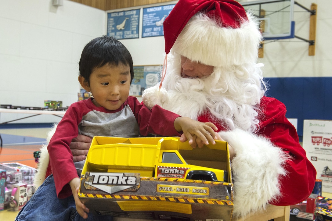 A child receives a gift from Santa Claus during Toys for Tots at Nunachiam Sissauni School in Buckland, Alaska, Nov. 29, 2016. Santa was assisted by by Marine Corps 1st Sgt. Joshua Guffey, the inspector-instructor first sergeant assigned to Detachment Delta, 4th Law Enforcement Battalion. Air Force photo by Alejandro Pena