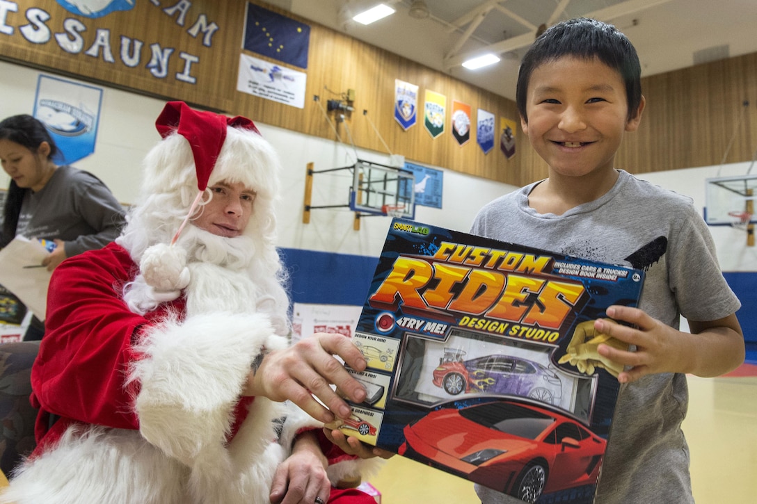 A young boy smiles after receiving a gift from Santa Claus during Toys for Tots at Nunachiam Sissauni School in Buckland, Alaska, Nov. 29, 2016. Santa was assisted by by Marine Corps 1st Sgt. Joshua Guffey, the inspector-instructor first sergeant assigned to Detachment Delta, 4th Law Enforcement Battalion. Air Force photo by Alejandro Pena