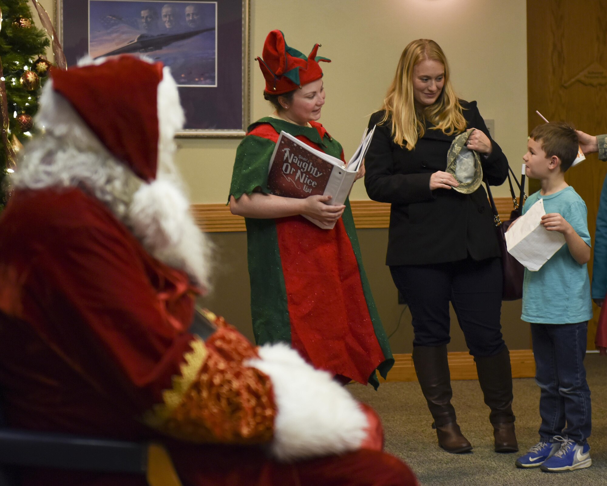 A volunteer dressed as an elf, center left, listens to a child, right, explaining why he should be on the nice list before meeting Santa during the annual tree lighting event at Whiteman Air Force Base, Mo., Nov. 29, 2016. Approximately 1,400 people attended the event, which was made possible by a total of 16 volunteers.