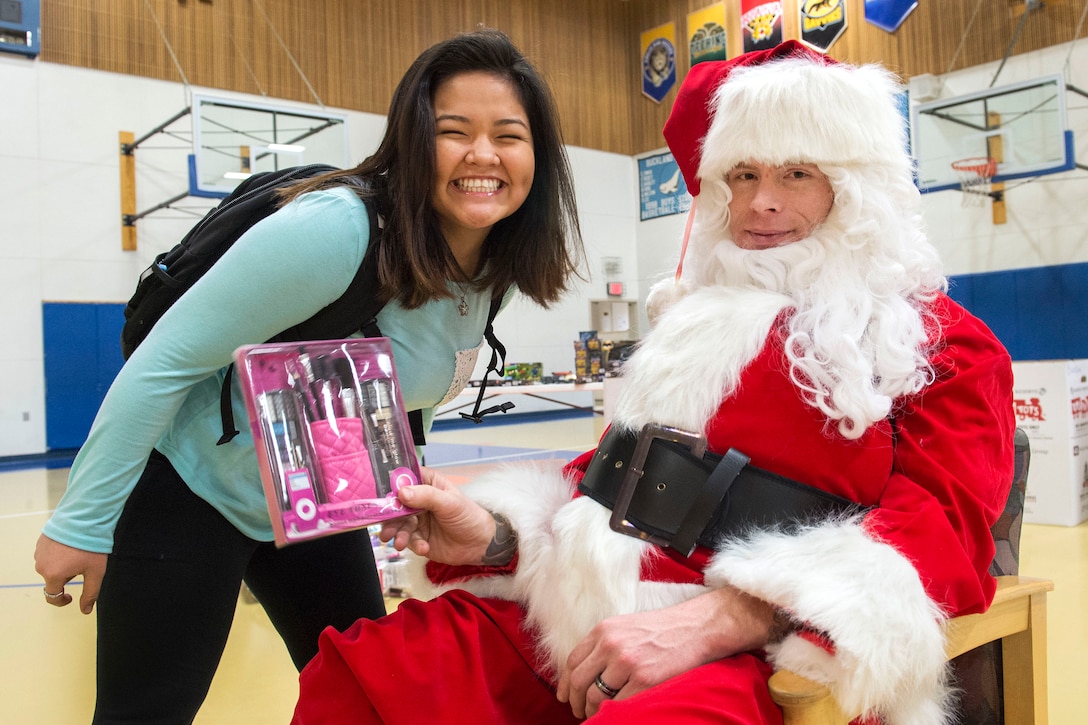 A student smiles for a photograph with Santa Claus during Toys for Tots at Nunachiam Sissauni School in Buckland, Alaska, Nov. 29, 2016. Santa was assisted by by Marine Corps 1st Sgt. Joshua Guffey, the inspector-instructor first sergeant assigned to Detachment Delta, 4th Law Enforcement Battalion. Air Force photo by Alejandro Pena