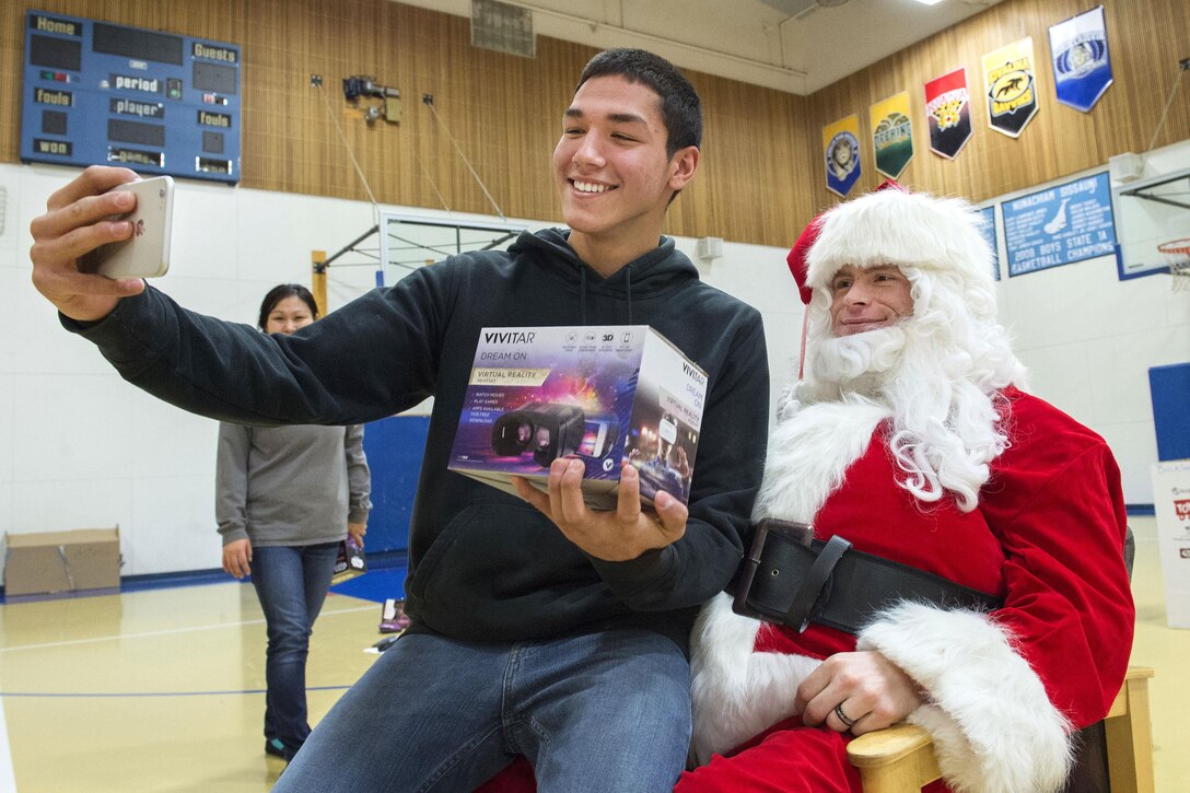 Jacob, left, 15, takes a selfie with Santa Claus during Toys for Tots at Nunachiam Sissauni School in Buckland, Alaska, Nov. 29, 2016. Santa was assisted by by Marine Corps 1st Sgt. Joshua Guffey, the inspector-instructor first sergeant assigned to Detachment Delta, 4th Law Enforcement Battalion. Air Force photo by Alejandro Pena